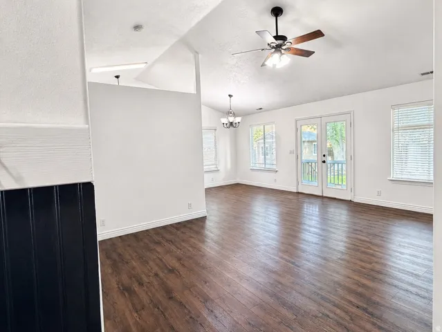 Vaulted ceilings with a ceiling fan, wood-finish flooring, white walls, and French doors