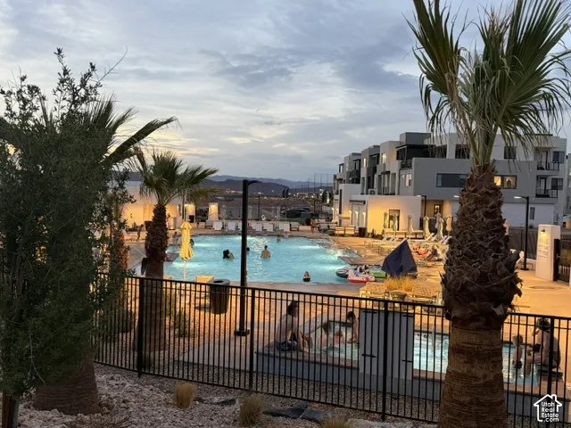 Outdoor swimming pool with integrated spa, surrounded by lounge seating and mature palm trees, featuring modern building architecture in the background