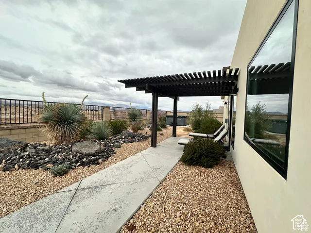 Modern exterior with a black slatted pergola, expansive fixed windows, and a concrete paver walkway