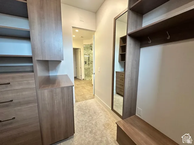 Custom built-in wood-finish shelving, integrated drawers with dark hardware, a full-length mirror, and tile flooring