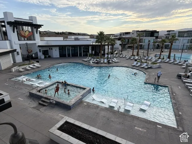 Expansive swimming pool with integrated spa and numerous poolside lounge chairs