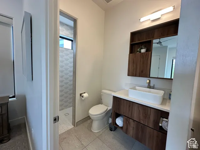 Modern vanity with wood-finish cabinetry, white countertop, and vessel sink