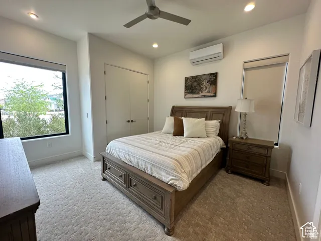 Recessed lighting, ceiling fan, split-system air conditioning unit, large window, and light-toned carpet