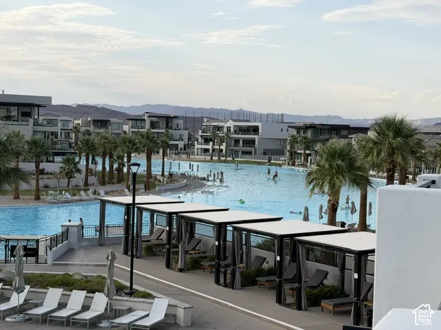 Expansive artificial lagoon with multiple water features, surrounded by modern residential structures, cabanas, and mature palm trees