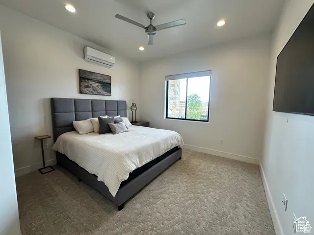 Recessed ceiling lighting, ceiling fan, wall-mounted air conditioning unit, light-toned carpeting, and a window with a dark frame