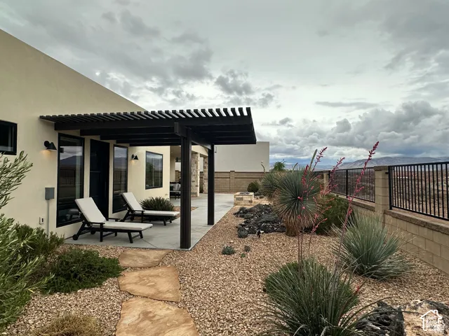Stucco exterior with a dark-stained wood pergola and concrete patio