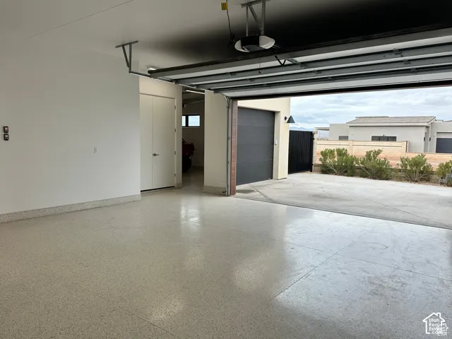 Spacious garage featuring polished concrete flooring, overhead garage door with integrated opener, interior access door, and abundant natural light from the open bay