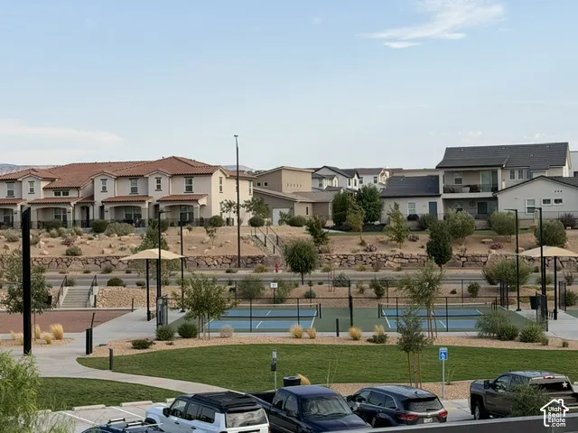 Community hardscaping with a tennis court, manicured lawn, and paved walkways