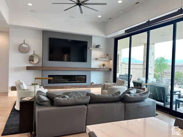 Spacious living area featuring a linear fireplace, wood-finish mantel, recessed lighting, and large sliding glass doors opening to an outdoor patio with stone columns