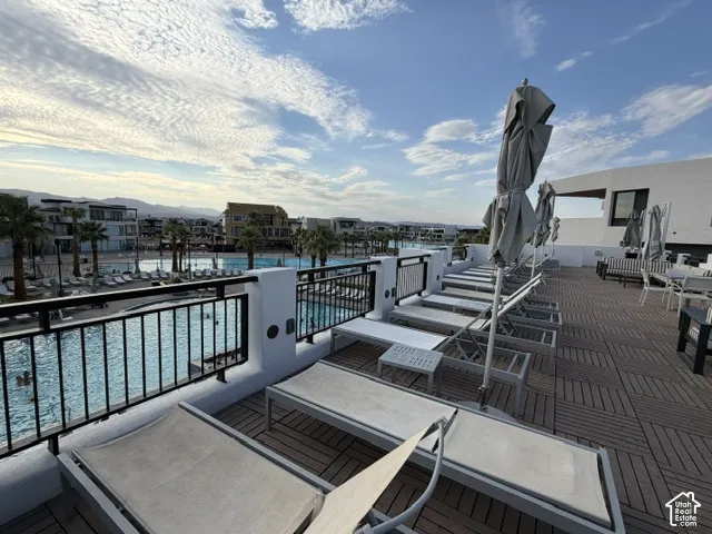 Rooftop patio with wood-finish decking, black metal railings, and a large communal swimming pool