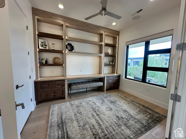 Built-in cabinetry with integrated lighting, wood-finish flooring, recessed lighting, ceiling fan, and a large window