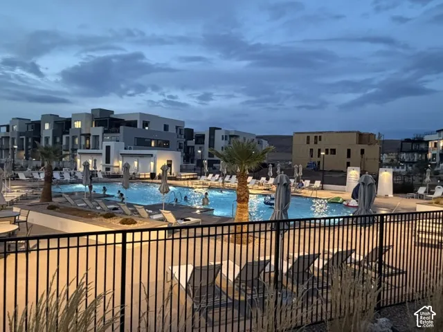 Resort-Style Community Pool and Spa with Illuminated Lounge Areas, Mature Landscaping, and Modern Multi-Story Residential Buildings Surrounding the Amenity Space