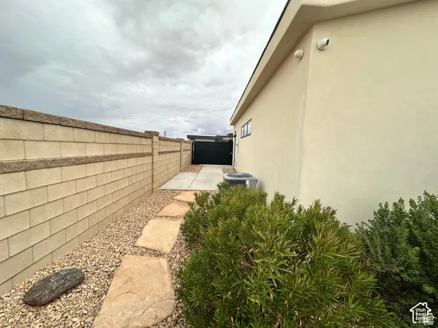 Stucco exterior with a rock and paver pathway, featuring a block wall and established landscaping