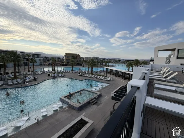 Expansive pool area featuring multiple swimming pools, an integrated spa, surrounding lounge seating, and mature palm trees