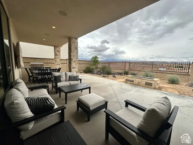 Expansive covered patio with stone-clad columns, recessed lighting, and a built-in outdoor grill