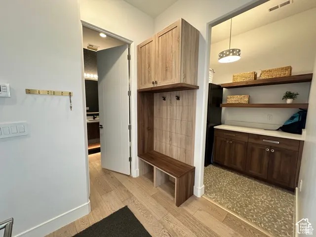 Welcoming foyer featuring wood-finish flooring, custom built-in cabinetry with upper shelving and lower storage, and warm wood-tone finishes