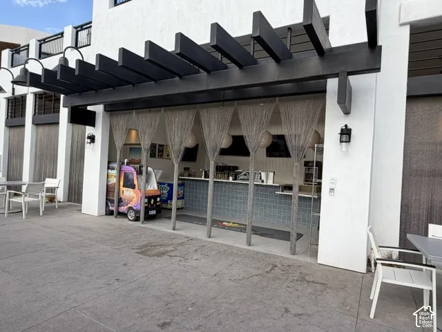 Pergola-covered outdoor counter with textured wall tile and overhead lighting
