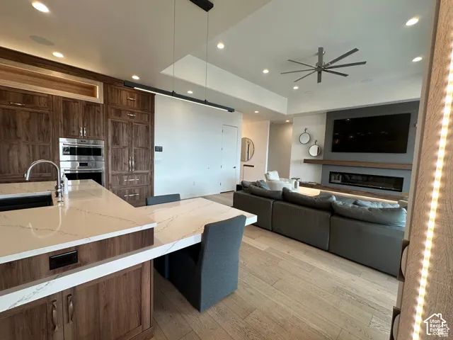 Kitchen island with integrated seating, stainless steel appliances, wood-finish cabinetry, recessed lighting, and a modern linear fireplace