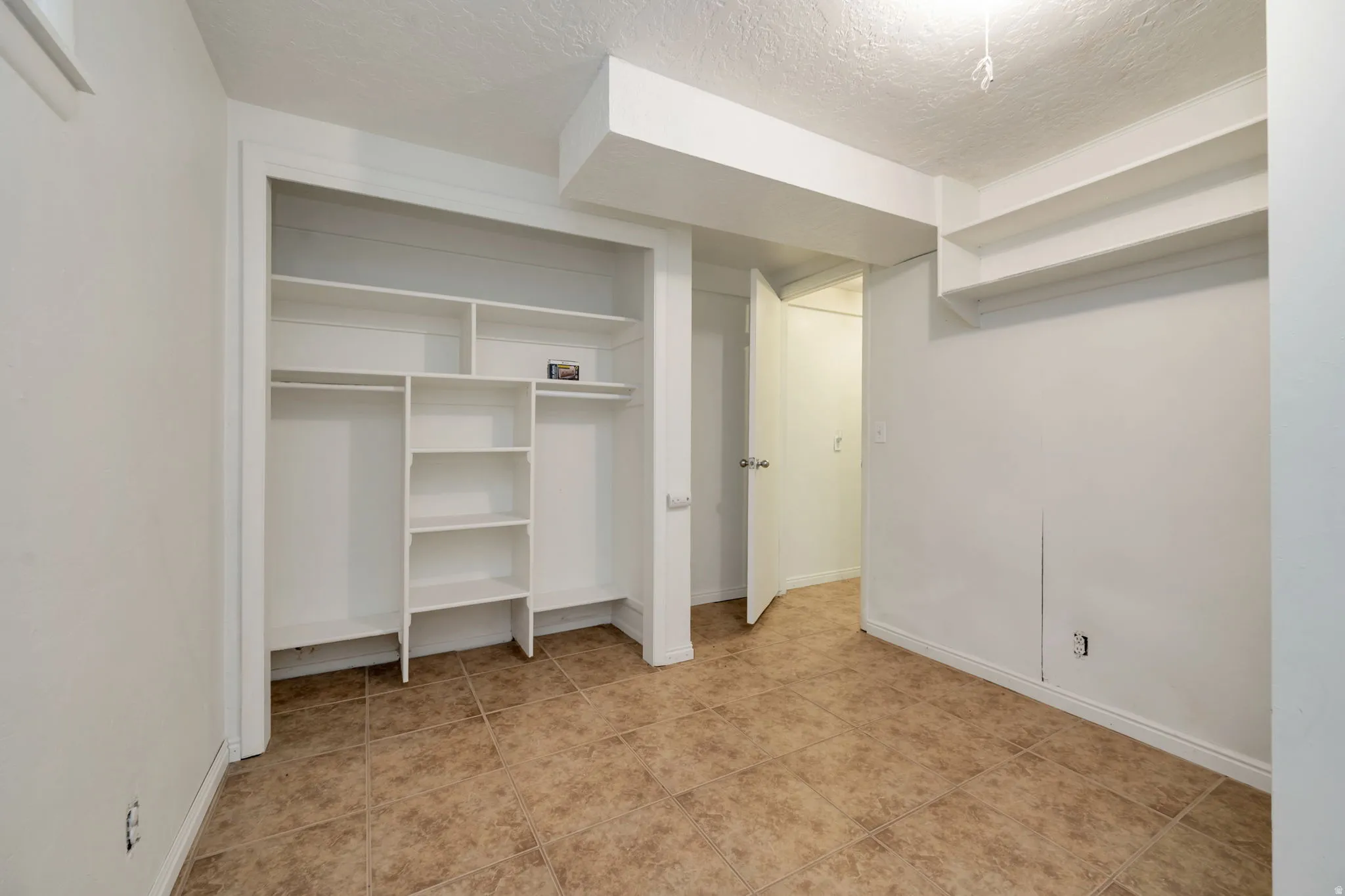 Spacious walk-in closet featuring custom shelving and hanging storage throughout, cork-finish flooring, and recessed lighting for optimal visibility and organization