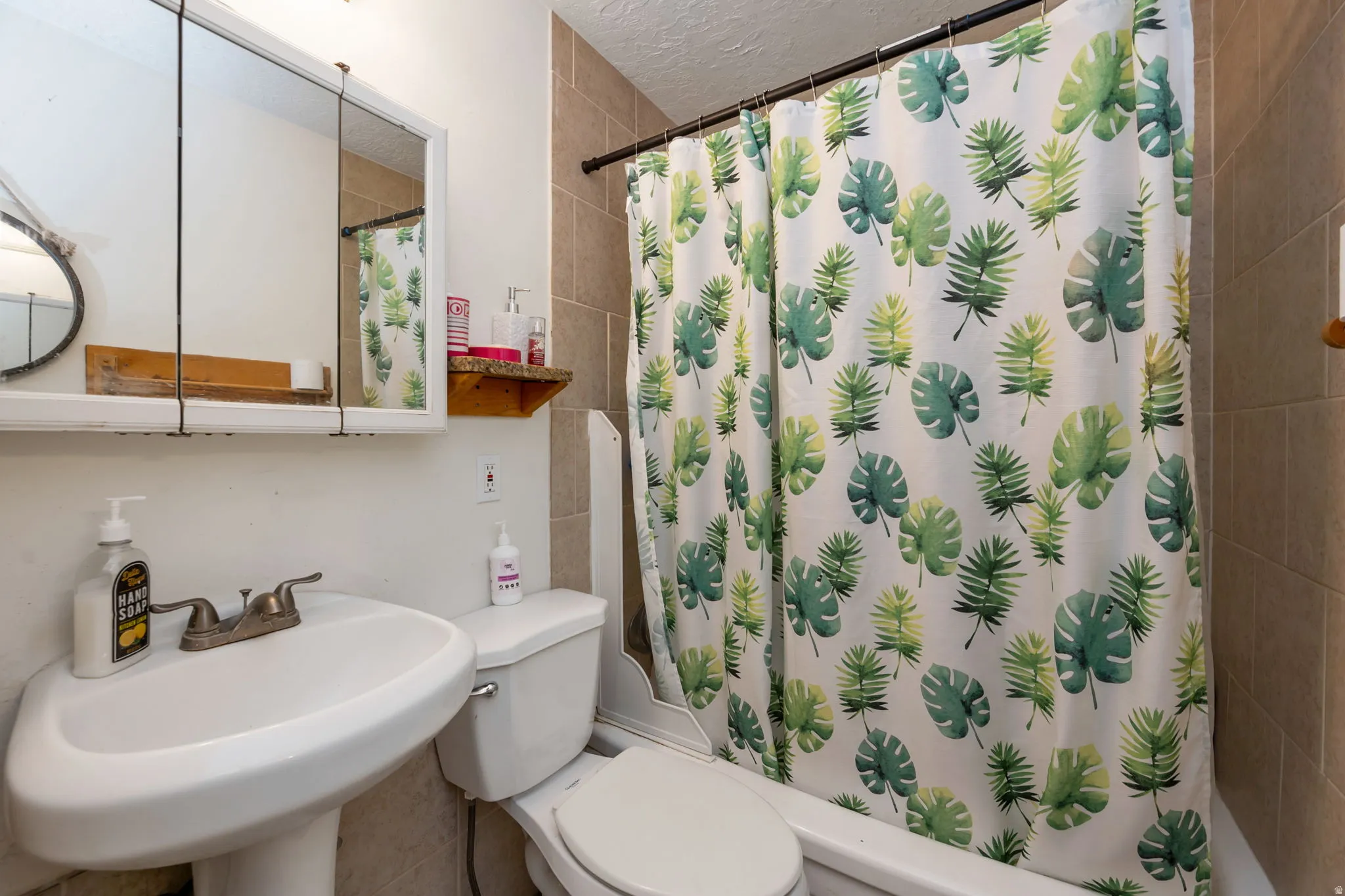 Full bathroom featuring a curved pedestal sink with widespread faucet, toilet, and tile surround