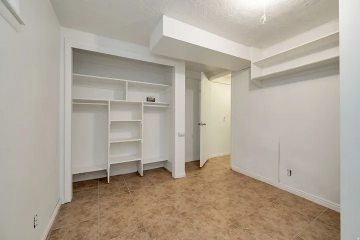 Spacious walk-in closet featuring custom shelving and hanging storage throughout, cork-finish flooring, and recessed lighting for optimal visibility and organization