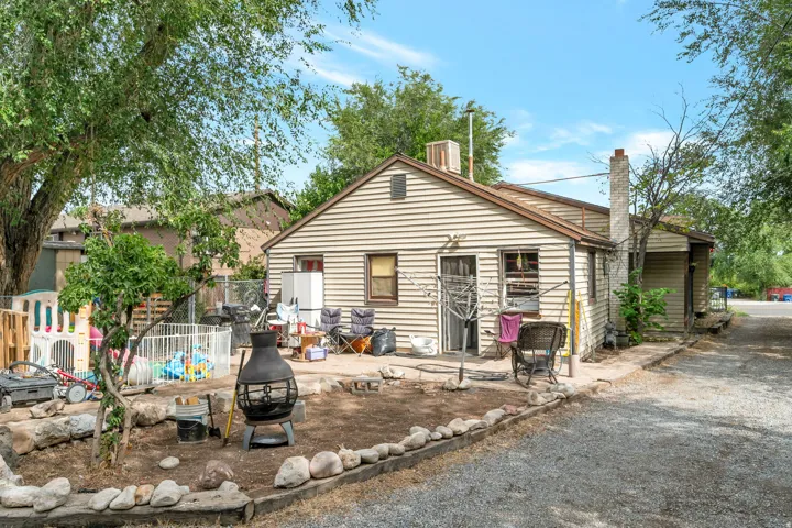 Siding exterior with a stone chimney and gravel driveway