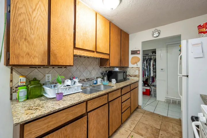 Kitchen featuring wood cabinetry, light-toned countertops, a tile backsplash, and a double basin sink