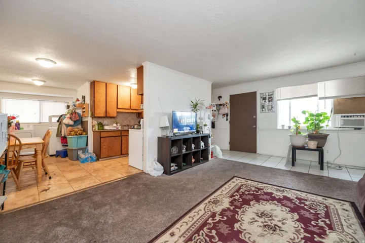 Open-concept living space featuring wood-finish flooring, warm wood cabinetry, and built-in shelving