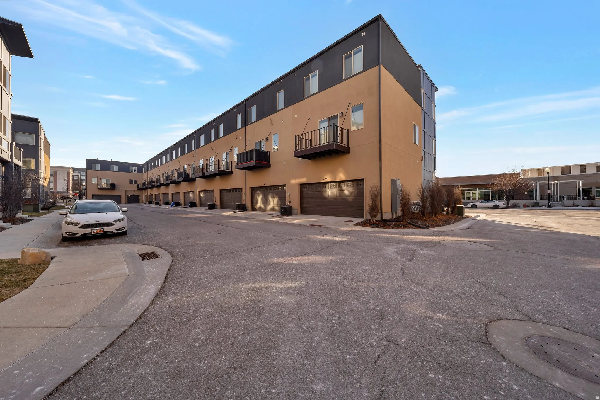Contemporary townhomes featuring integrated garages, private balconies, and a paved drive