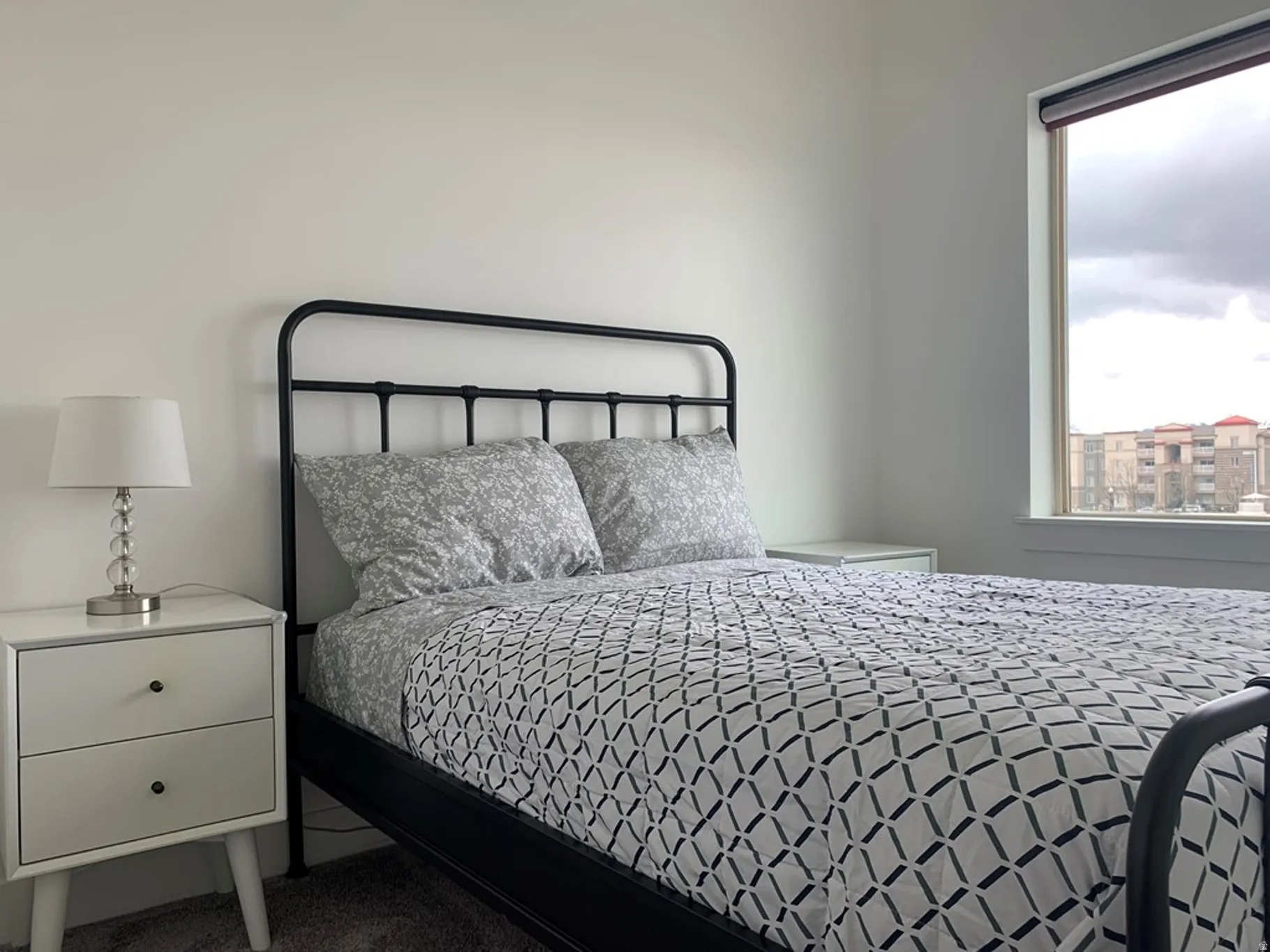 White walls with a single window, featuring a roller shade