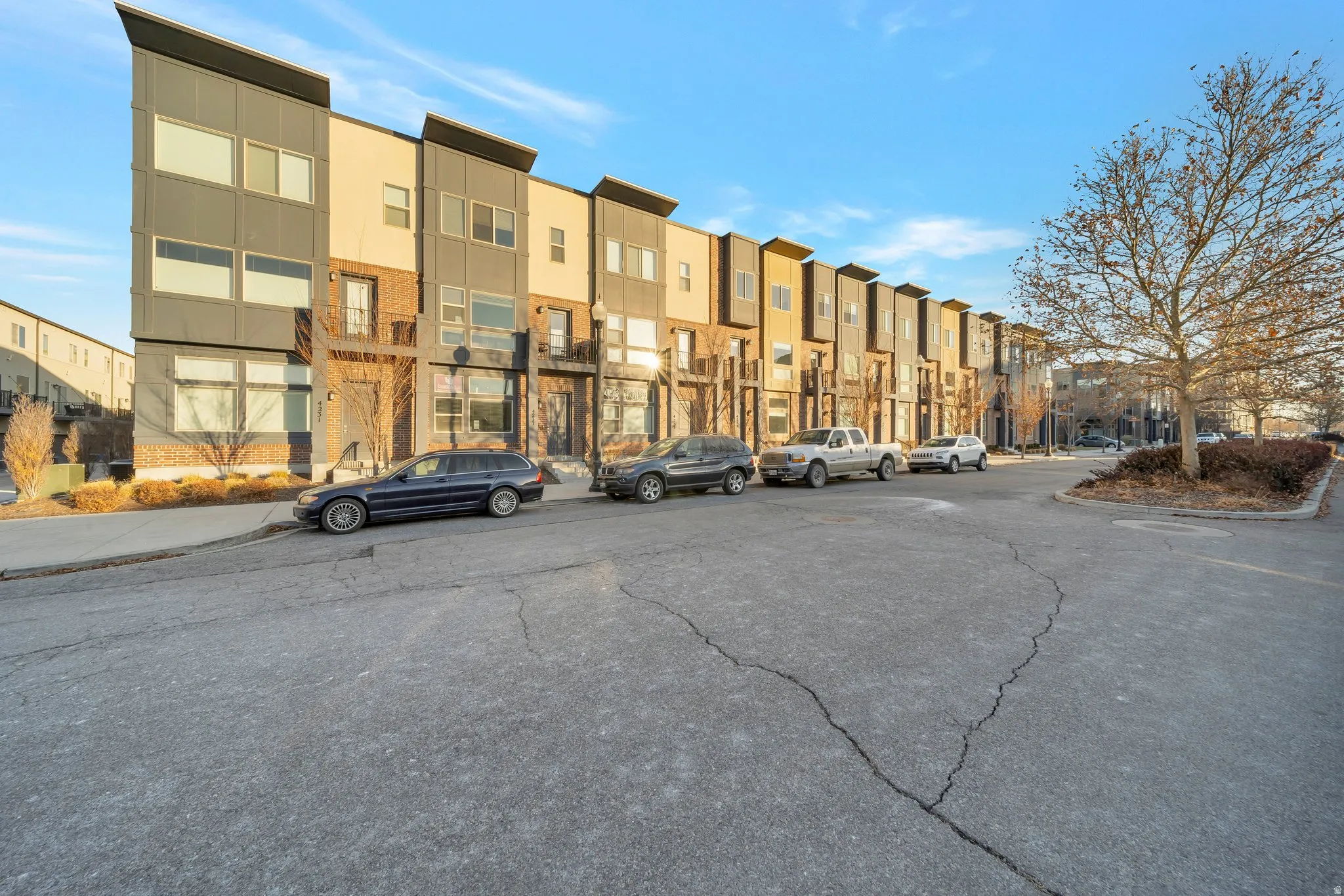 Modern townhome exterior with mixed material facade, clean lines, large windows, and a multi-level design