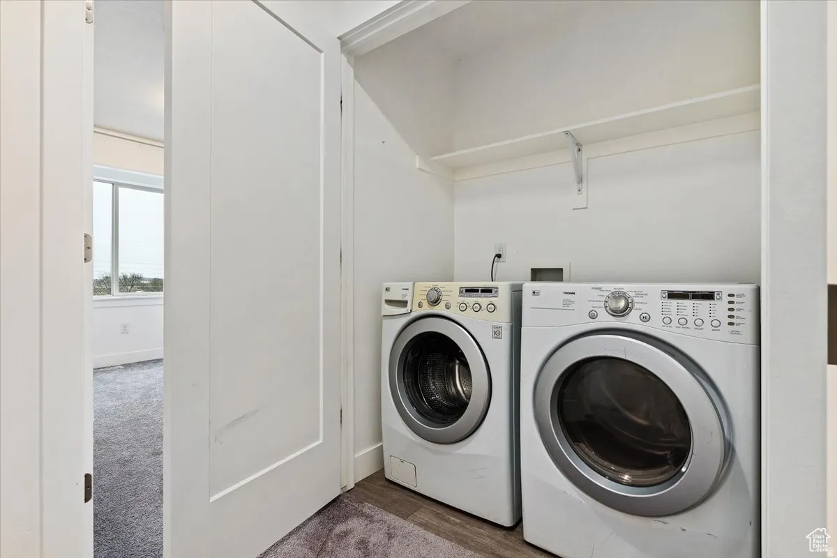 Dedicated laundry closet with built-in shelving, wood-finish flooring, and a pair of front-loading appliances