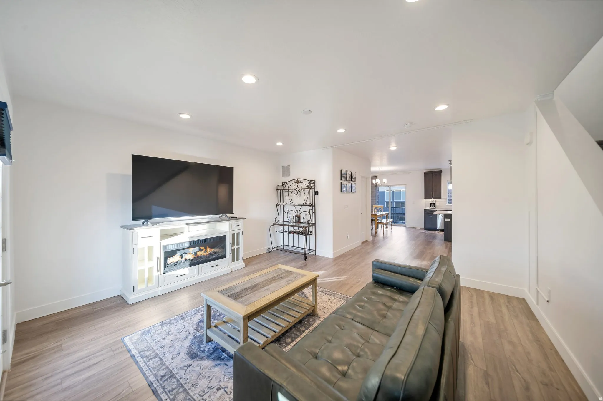 Recessed lighting illuminates the living area with wood-finish flooring