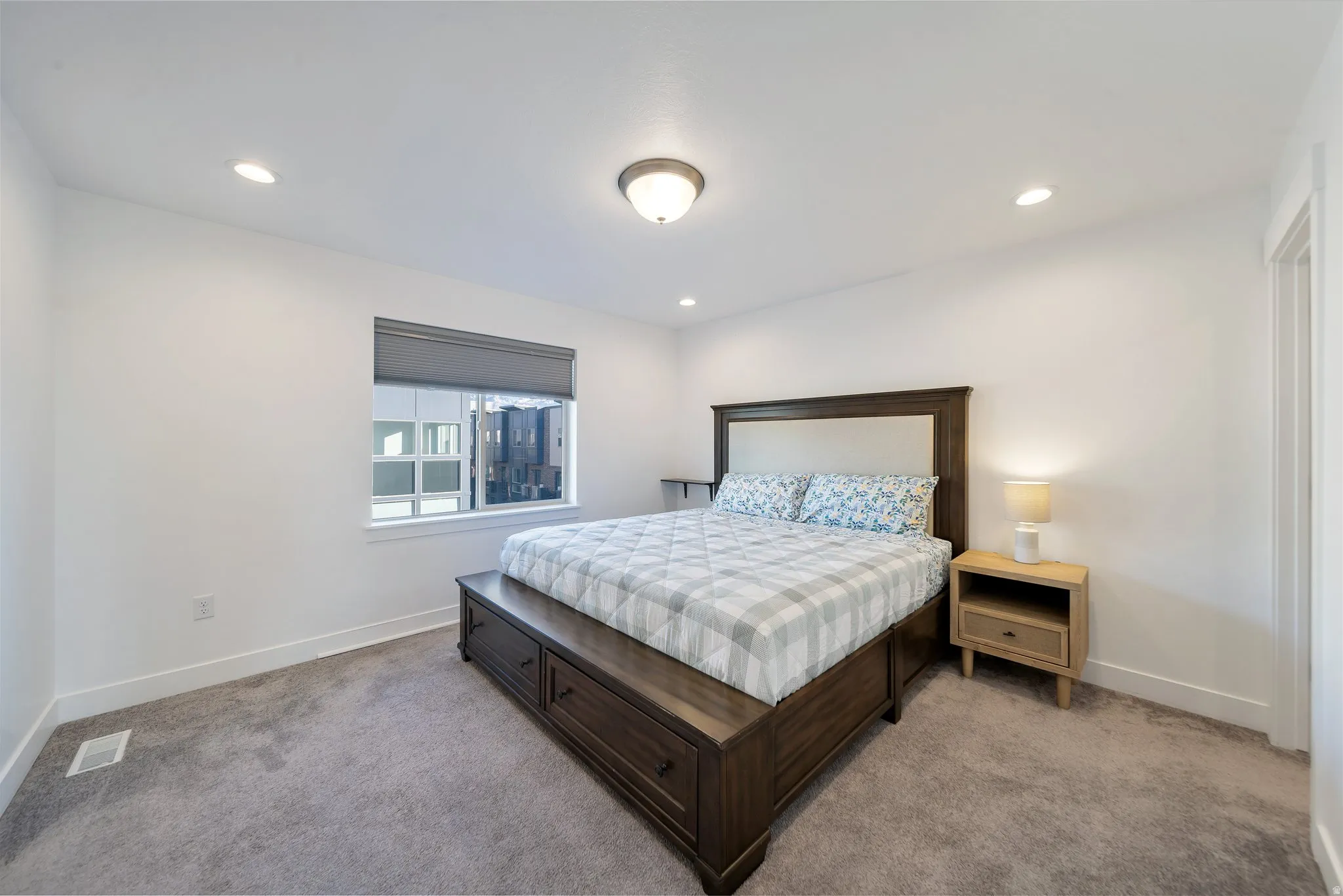 Recessed ceiling lighting, flush mount ceiling fixture, window with roller shade, carpeted flooring, and a solid core door