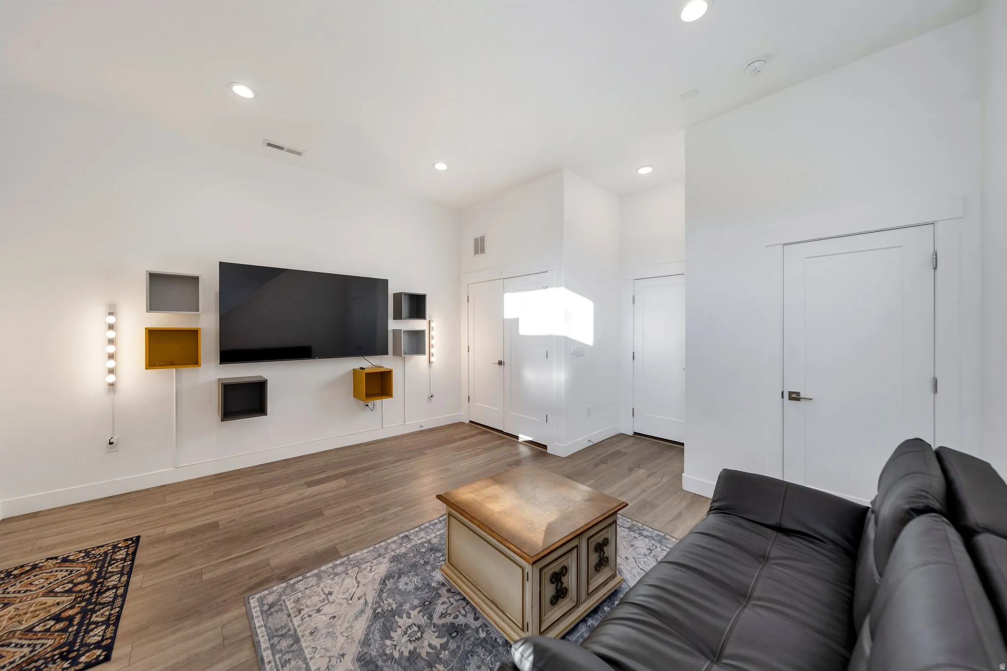 High ceilings, wood-finish flooring, recessed lighting, and wall-mounted light fixtures