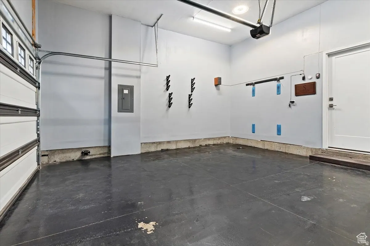 Attached garage with a roll-up door, overhead lighting, and an additional access door