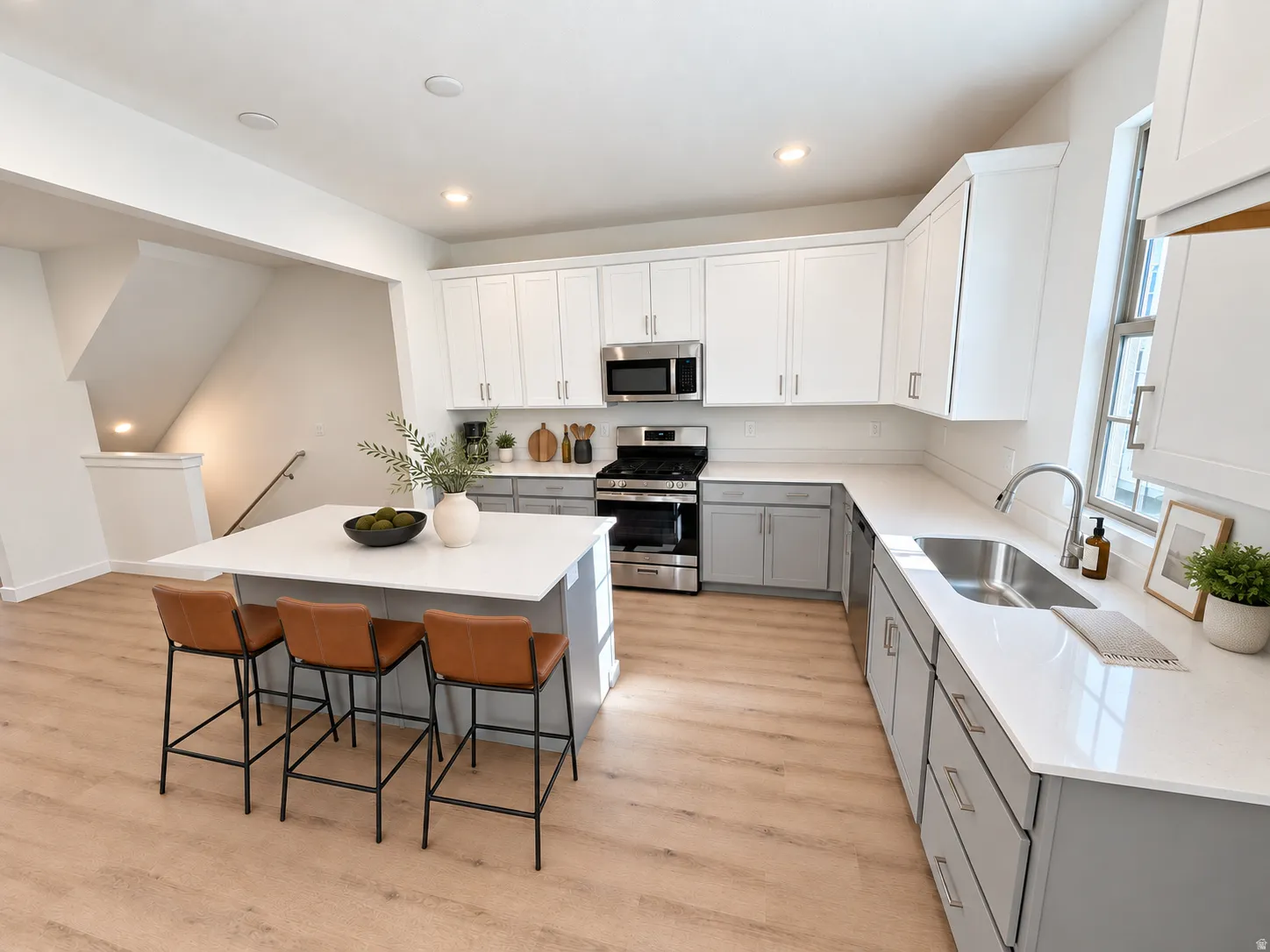 Kitchen featuring a central island, stainless steel appliances, white cabinetry, light gray base cabinetry, and wood-finish flooring
