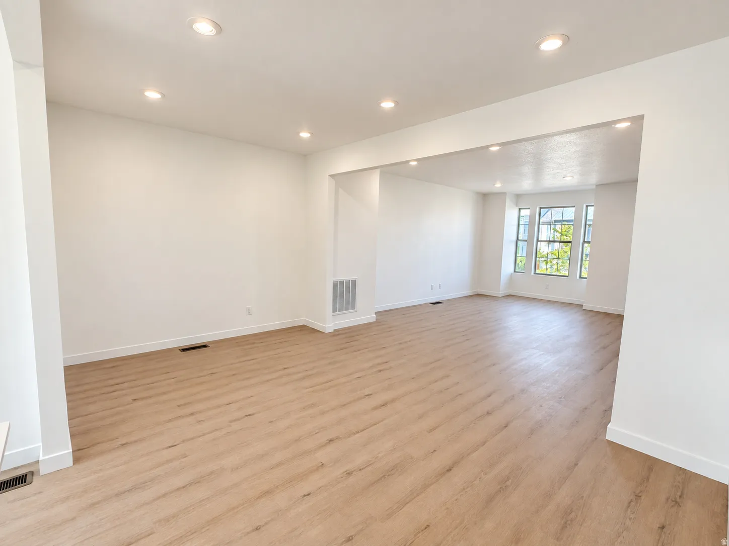 Recessed lighting, wood-finish flooring, white walls, and a bay window with multiple panes