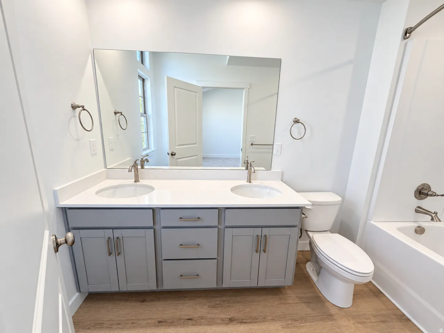 Dual vanity with undermount sinks, stone-finish countertop, brushed nickel fixtures, and wood-finish flooring