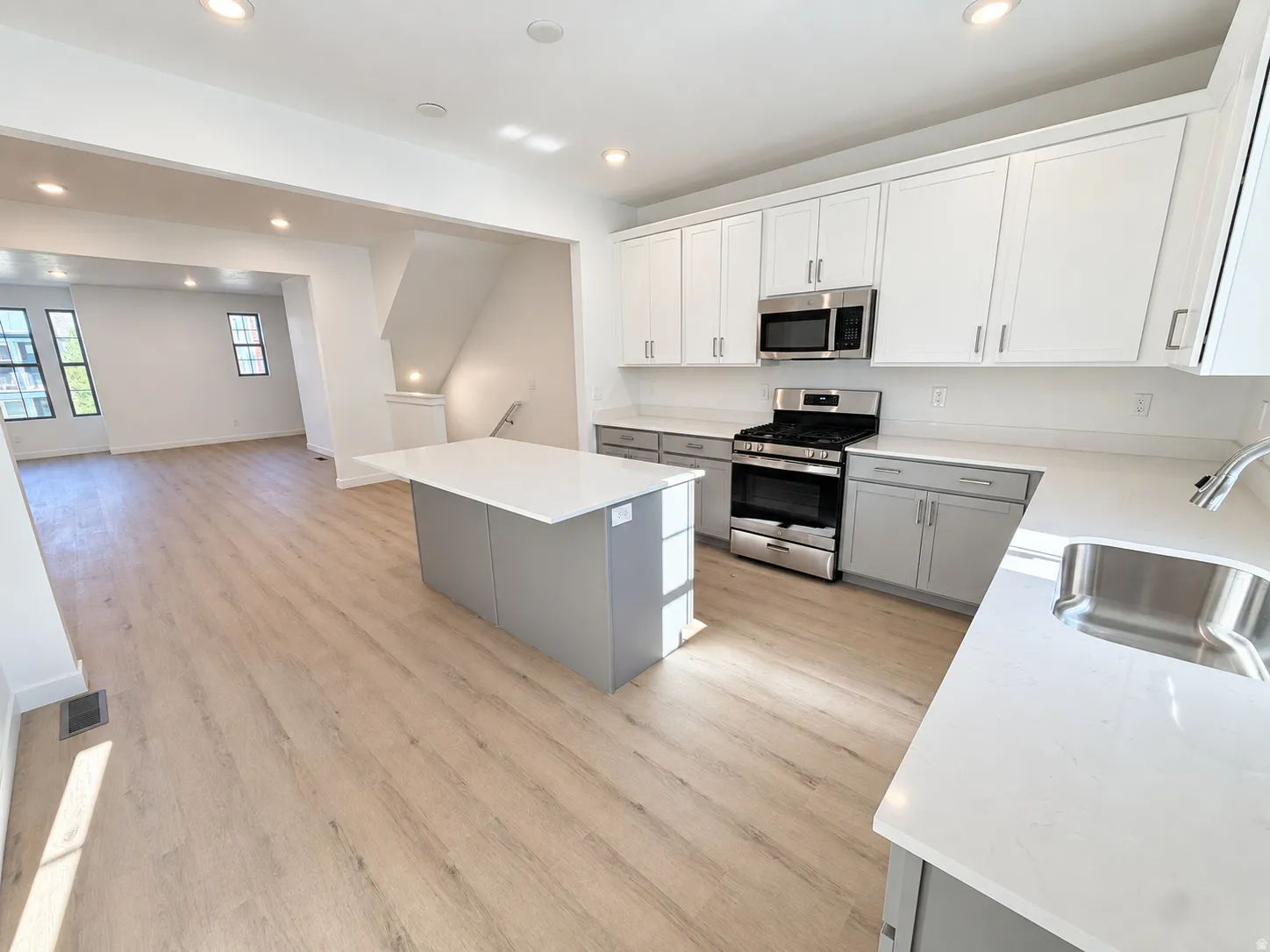Modern kitchen featuring stainless steel appliances, a center island, white cabinetry, light wood-finish flooring, and recessed lighting