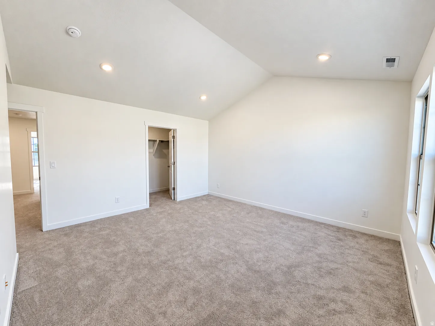 Vaulted ceiling, recessed lighting, neutral tone carpet, white trim, and a built-in closet