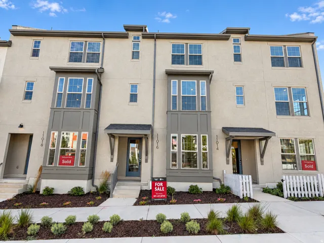 Contemporary townhome facade with stucco exterior, multiple window configurations, and covered entryways