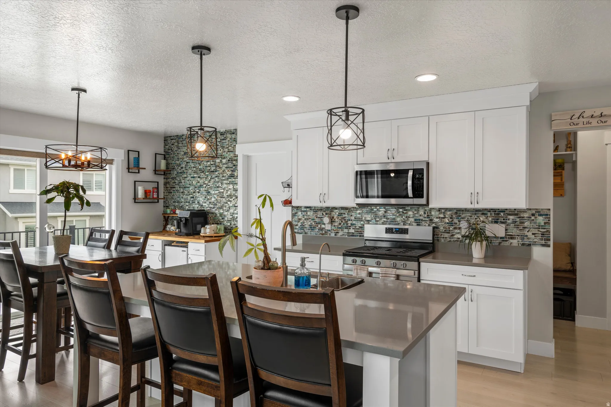 Here you will find quartz counters, a large island, white cabinets, & custom lighting.