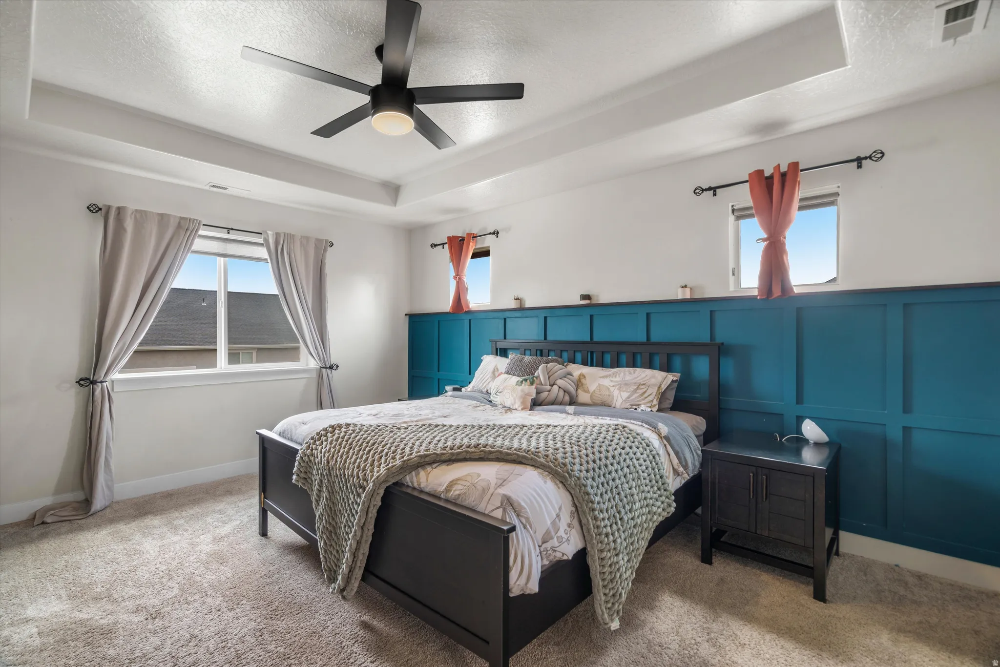 Ceiling fan, wainscoting, alcove ceiling, and an abundance of windows can be found in the primary bedroom.