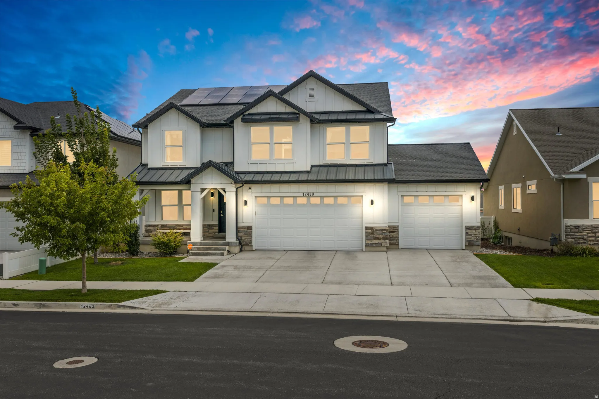 Modern farmhouse exterior with white siding, dark trim, and stone accents