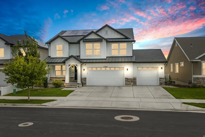 Modern farmhouse exterior with white siding, dark trim, and stone accents