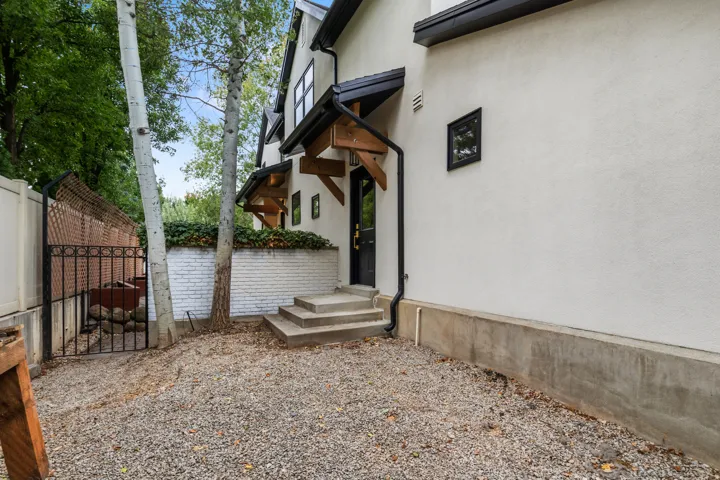 Stucco exterior with a black trim window, concrete foundation, and gravel ground cover