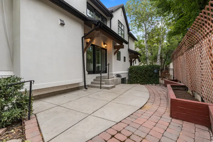 Exterior patio featuring concrete and paver sections, raised garden beds, and a lattice fence