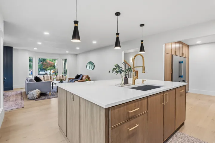 Kitchen island with a white countertop and integrated sink, gold-finish faucet, and wood-finish cabinetry