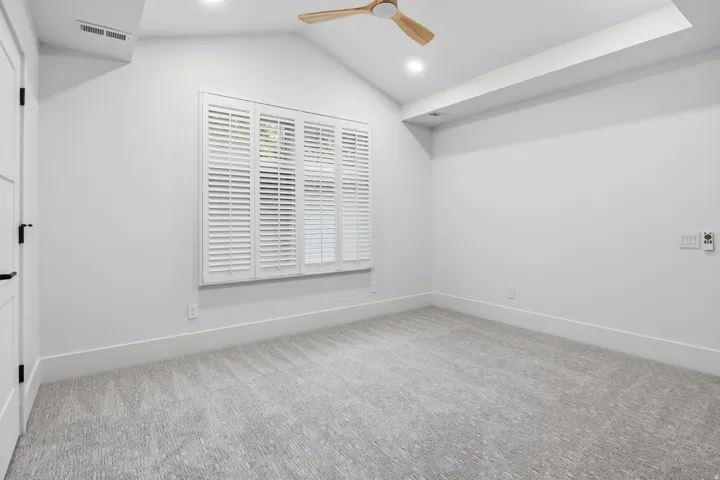 Vaulted ceiling with a wood-tone ceiling fan, recessed lighting, plantation shutters, and light grey patterned carpeting